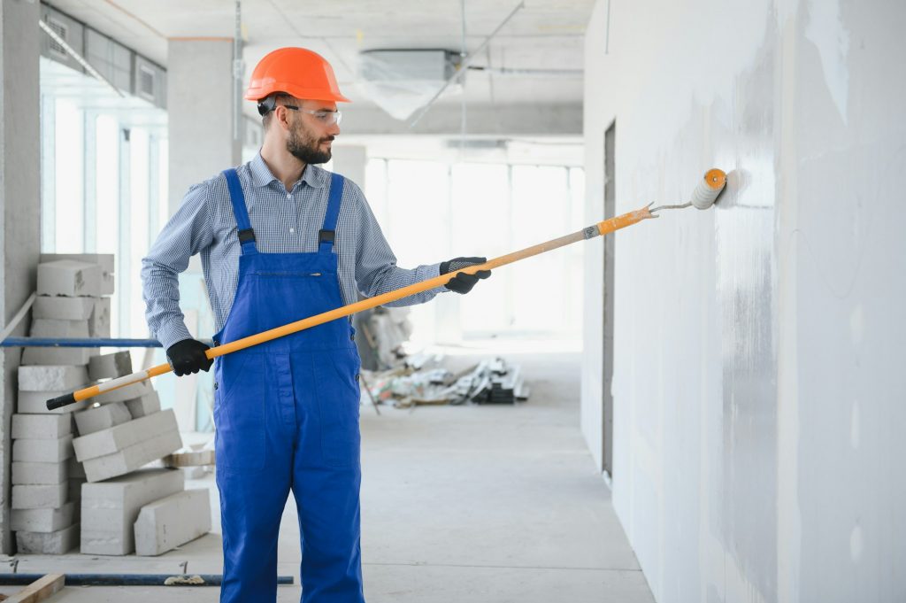 Painter in uniform paints the wall.