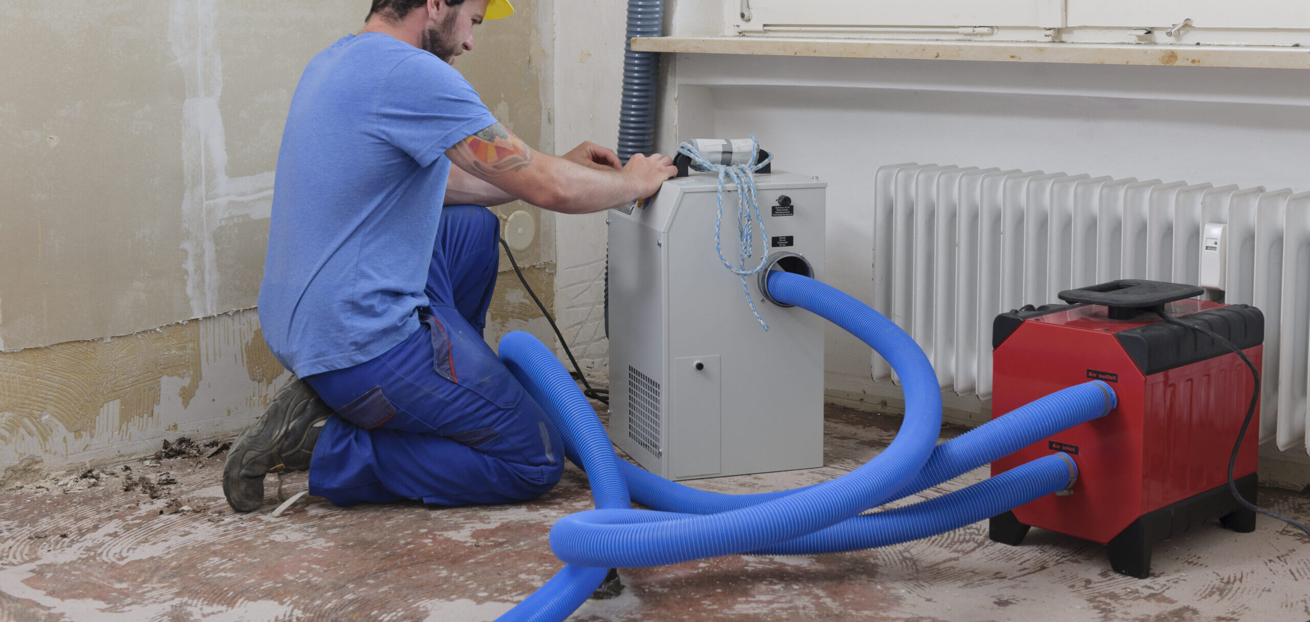 Arbeiter stellt Luftentfeuchter in einer Wohnung ein, die durch Überschwemmung beschädigt wurde